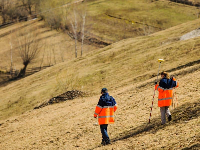 Surveyors collecting elevation data on a steep hillside property in Colorado Springs to support topographic survey planning.