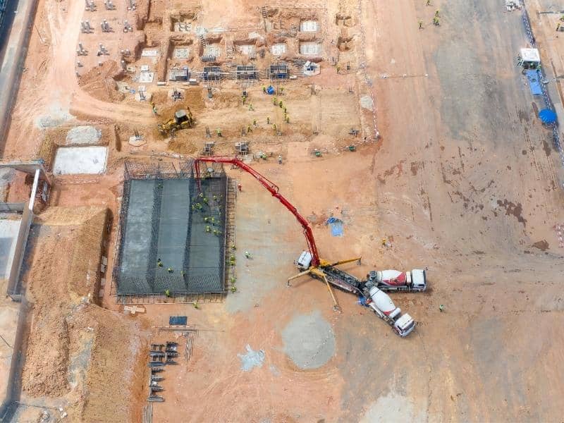 Aerial view of an active construction site with machinery, foundation work, exposed ground, and open areas used for drone LiDAR terrain planning.